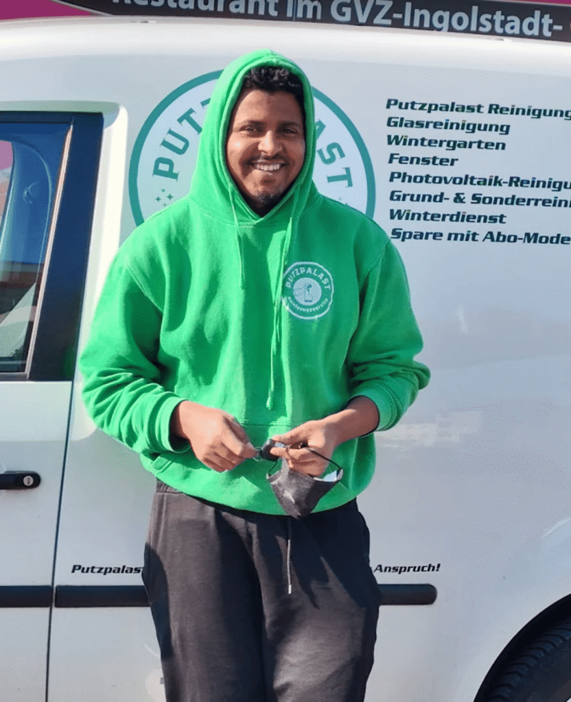 Putzpalast Mitarbeiter im grünen Hoodie vor dem Firmenfahrzeug